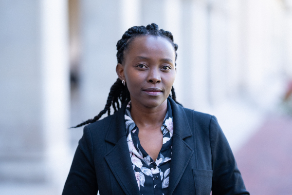 A dark skinned woman with braids poses for a professional head shot.