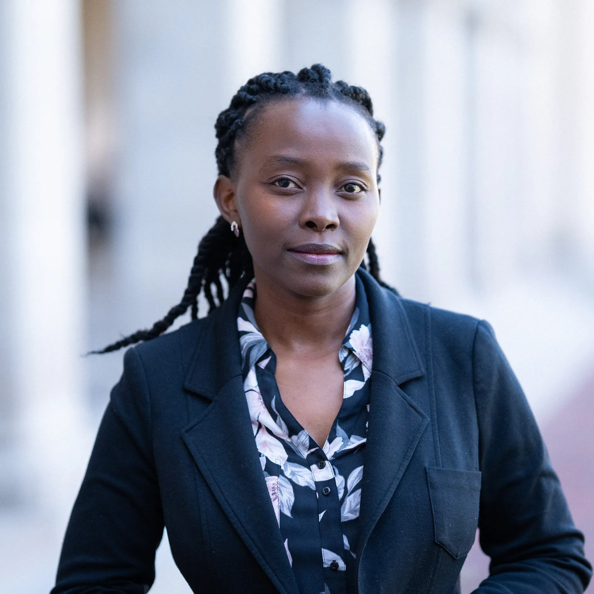 A dark skinned woman with braids poses for a professional head shot.